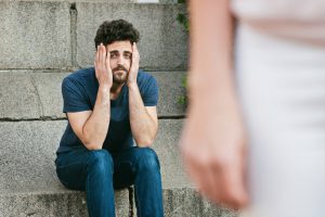 Man sitting with his hands on his face looking defeated